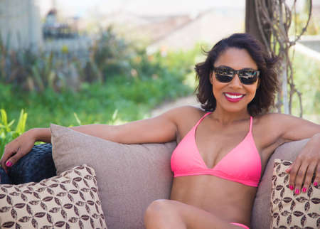 Woman in bikini relaxing on sofa outdoorsの写真素材