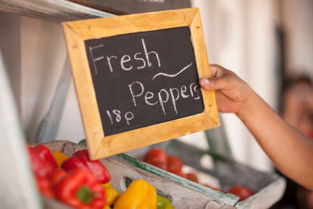 Hand holding signage with words "Fresh Peppers 18p"の写真素材
