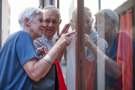 Senior couple pointing at city shop windowの写真素材
