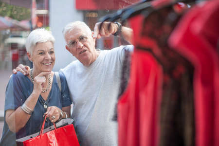 Senior couple shopping for dress in city shop windowの写真素材