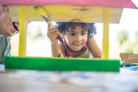 Father and son doing crafts together, painting wooden birdhouseの写真素材