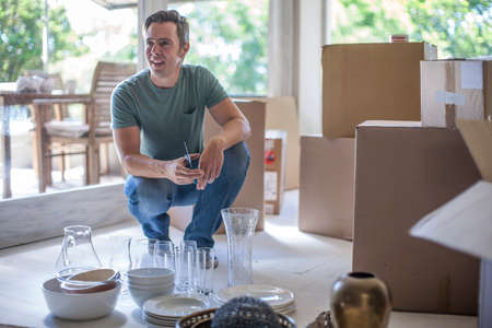 Moving house: man preparing to pack glasswareの写真素材