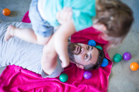 Father lying on floor, carrying daughter up in mid airの写真素材