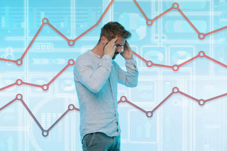 Man touching temples, stressed expression, graphical screen with data behind him