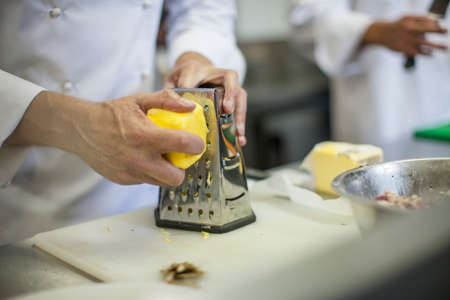 Chef grating cheese in kitchenの写真素材