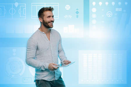 Man using digital tablet, graphical screen with gaming images behind himの写真素材