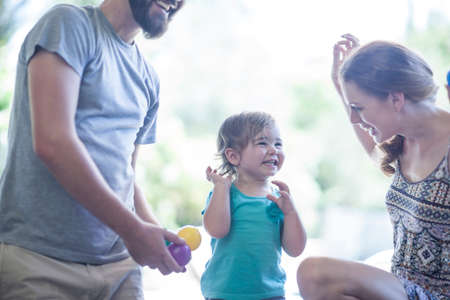 Parents and daughter playing with balls on floor