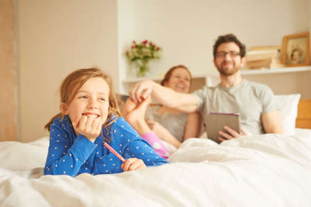 Mid adult couple tickling daughters bare feet whilst having  lie inの写真素材