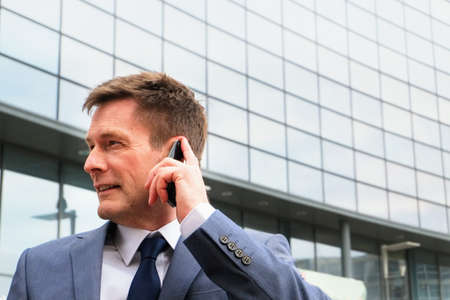 Mature businessman outdoors, using smartphoneの写真素材