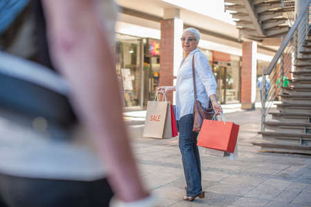 Mature woman shopper waiting for friend in shopping mallの写真素材