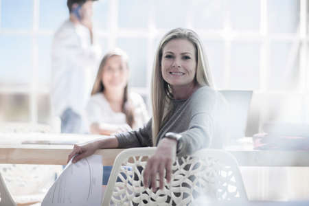 Portrait of female designer holding blueprint in design studioの写真素材