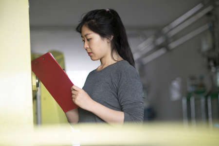Worker writing on clipboard in factoryの写真素材