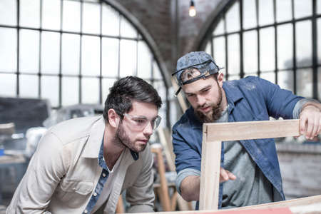Craftsmen inspecting frame in antique restoration workshopの写真素材
