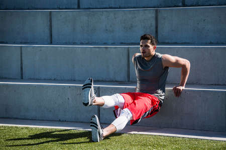 Young man training, doing push up on playing field stairway