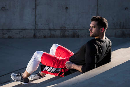 Young man training, taking a break on city stairs