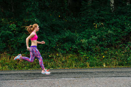 Teenage girl running along rural roadの写真素材