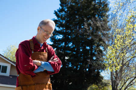 Senior man wearing carpenters apron in gardenの写真素材