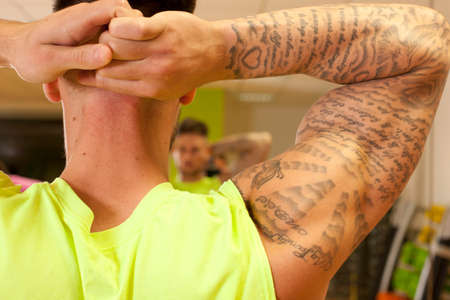 Rear view of tattooed man hands behind head doing stretching exerciseの写真素材