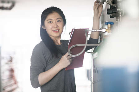 Worker checking readings on machine in factory