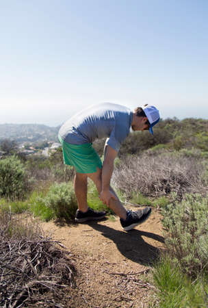 Man on mountain doing leg stretching exercisesの写真素材