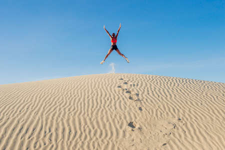 Runner jumping up with arms and legs outstretched in desert, Death Valley, California, USAの写真素材