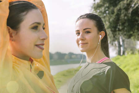 Two female friends exercising outdoors, stretching
