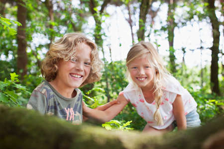 Boy and girl in forest looking at camera smilingの写真素材