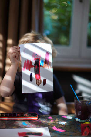 Portrait of girl holding up painting in front of herの写真素材