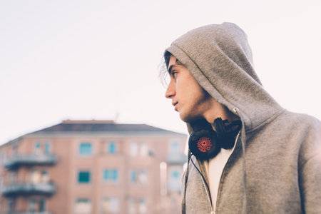 Portrait of man wearing hooded top and headphones looking away