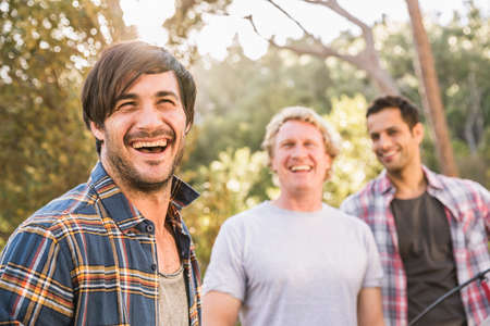 Three men laughing whilst putting up tent in forest, Deer Park, Cape Town, South Africaの写真素材