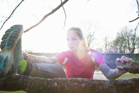Women leg raised on tree branch stretching