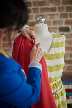 Rear view of woman in design studio draping fabric onto mannequinの写真素材