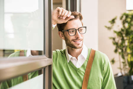 Cool businessman watching whilst leaning against office doorwayの写真素材