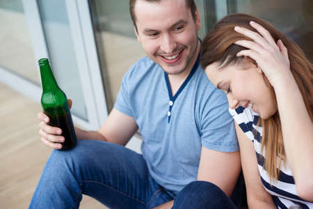 Young couple sitting outdoors, drinking bottled beerの写真素材