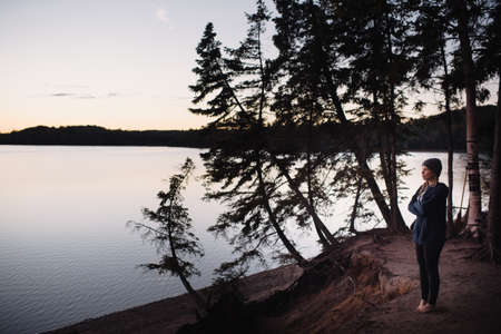 Mid adult woman standing beside lake, looking at viewの写真素材