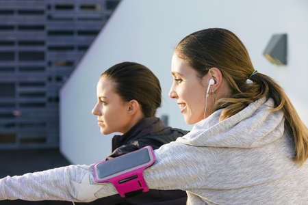 Young woman outdoors, wearing earphones and mp3 player on arm