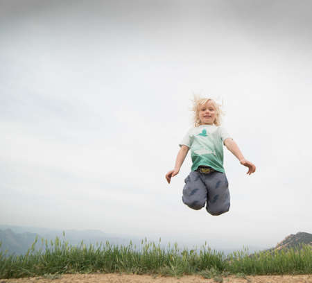 Boy jumping in mid air looking at camera smilingの写真素材