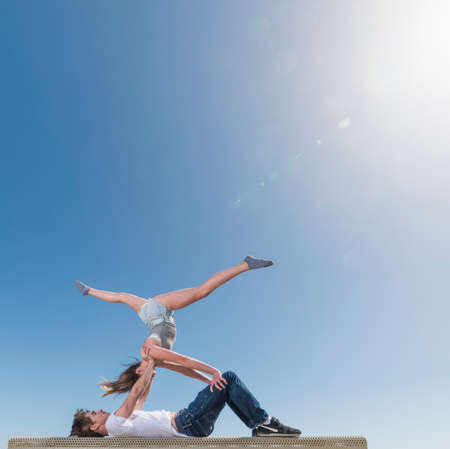 Couple practising partner yoga on benchの写真素材