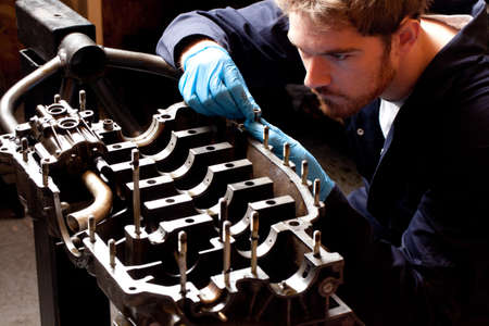 Male mechanic analysing car engine, stripped from carの写真素材