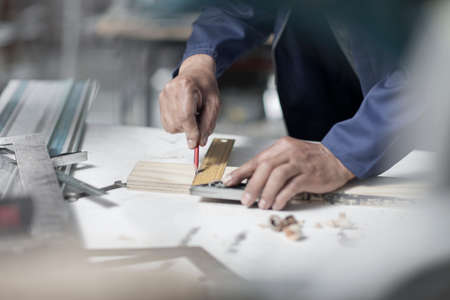 Hands of carpenter measuring angle wood on workshop bench
