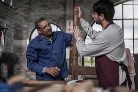 Carpenter working with trainee in workshop