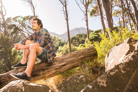 Male hiker sitting on fallen tree in forest, Deer Park, Cape Town, South Africa