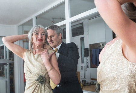 Couple dressing up getting ready in front of mirrorの写真素材