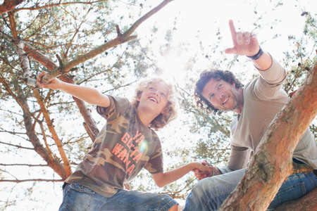 Father and son climbing treeの写真素材
