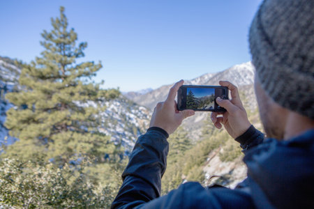 Hiker taking photograph of view, Mount Baldy, Californiaの写真素材