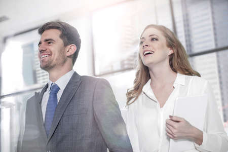 Businessman with businesswoman carrying digital tablet outside office buildingの写真素材