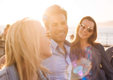 Three adult friends on sunlit pier, Santa Monica, California, USA