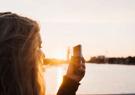 Woman taking photograph at sunset, Spree River, Berlin, Germanyの写真素材
