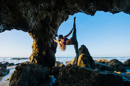 Young female ballet dancer poised on one leg in sea cave, Los Angeles, California, USAの写真素材