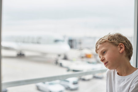 Boy looking out of airport windowの写真素材